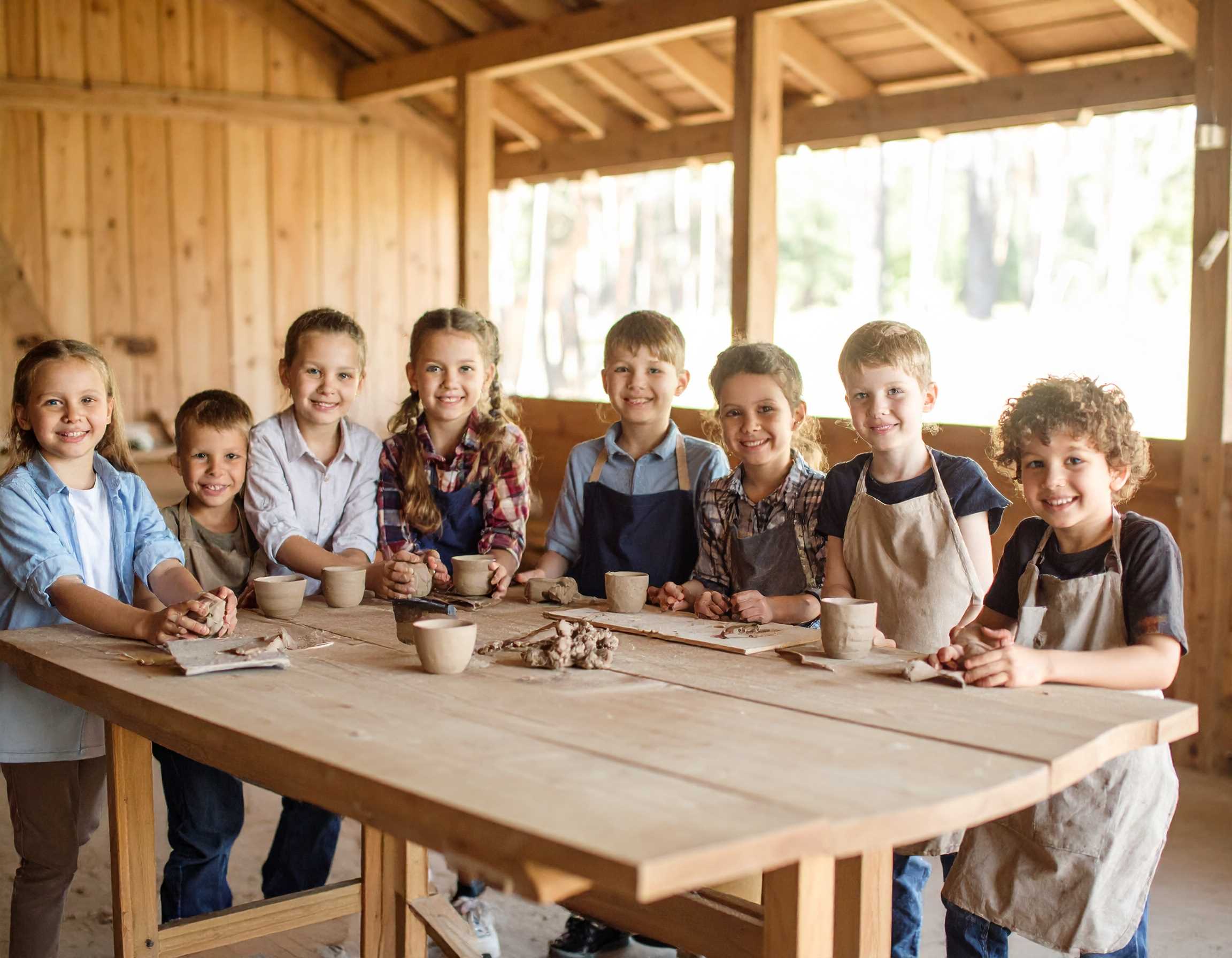 dzieci w wieku od 6 do 12 lat przy stole warsztaty garncarskie w stodole